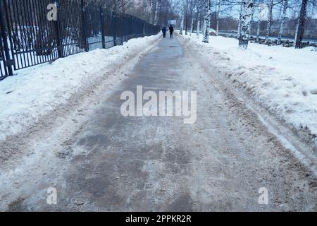 Petrozavodsk, Russland, 01,15. 2023 Schnee, Eis, Matsch und Winterschlamm auf dem Bürgersteig. Die Lufttemperatur beträgt etwa 0 °C. Schwierige Fahrbedingungen. Infrastruktur, Straßendienste. Straßenbelag mit nassem Schnee Stockfoto