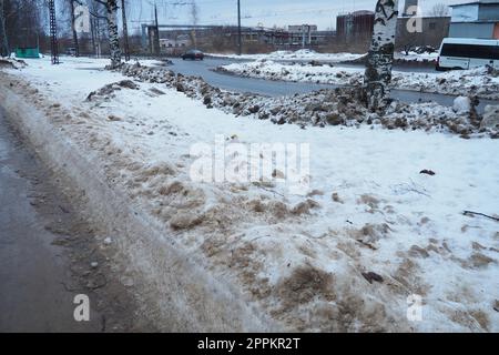 Petrozavodsk, Russland, 01,15. 2023 Schnee, Eis, Matsch und Winterschlamm auf dem Bürgersteig. Die Lufttemperatur beträgt etwa 0 °C. Schwierige Fahrbedingungen. Infrastruktur, Straßendienste. Straßenbelag mit nassem Schnee Stockfoto