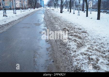 Petrozavodsk, Russland, 01,15. 2023 Schnee, Eis, Matsch und Winterschlamm auf dem Bürgersteig. Die Lufttemperatur beträgt etwa 0 °C. Schwierige Fahrbedingungen. Infrastruktur, Straßendienste. Straßenbelag mit nassem Schnee Stockfoto