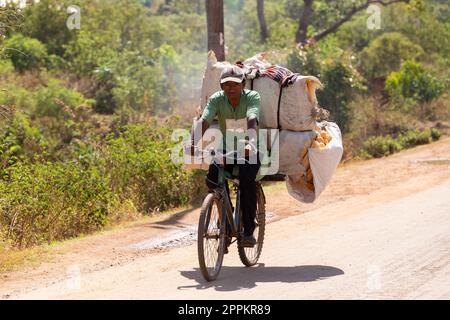 Ein madagassischer Mann auf einem Fahrrad transportiert große Säcke. Traditioneller Transport der armen Bevölkerung in Madagaskar Stockfoto