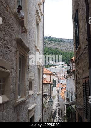 Dubrovnik, Kroatien, 08,14. 2022. Enge Gassen der antiken Stadt. Die Fassaden der Häuser sind aus Marmor und Stein sehr nahe beieinander. Fenster mit Fensterläden. Sommertourismus in der Adria. Stockfoto