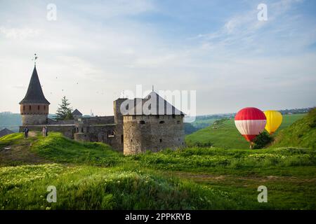 Kamianets-Podilskyi, Ukraine. Bunte Ballons fliegen über eine wunderschöne mittelalterliche Burg. Ballonfahrt für Touristen. Stockfoto