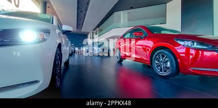 Auto parkt in einem luxuriösen Ausstellungsraum. Büro des Autohändlers. Neues rotes Auto im modernen Ausstellungsraum. Geschäftskonzept Auto zum Verkauf und zur Miete. Kfz-Leasing- und Versicherungskonzept. Autohändler. Stockfoto