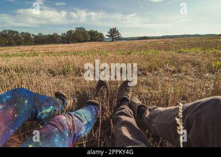 Touristen aus nächster Nähe, die sich auf der Wiese mit einem Konzeptfoto aus gemähtem Gras ausruhen Stockfoto