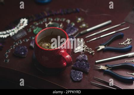 Nahaufnahme Schmuckmacher Kräutertee Tasse und Werkzeuge Konzeptfoto Stockfoto