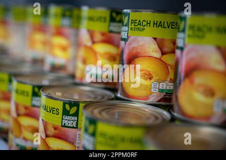 Pfirsichkonserven, die überschüssige Lebensmittel sind, werden im Pantry am St. Giles Trust in Camberwell, South London, einem lokalen Lebensmittelzentrum, angeboten. Foto: Montag, 24. April 2023. Stockfoto