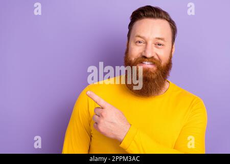 Porträtfoto eines jungen Promoters männlicher Kerl trägt ein gelbes, trendiges Hemd Direktfinger Modell neue Ladenpreise isoliert auf violettem Hintergrund Stockfoto