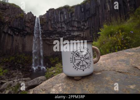 Nahaufnahme der Tasse auf dem Felsen vor dem Wasserfall Konzeptfoto Stockfoto