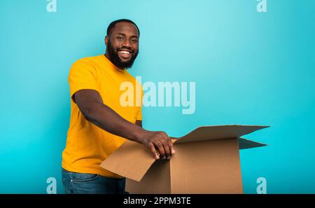 Happy Boy erhält ein Paket aus Online-Shop-Bestellung. Blauer Hintergrund. Stockfoto