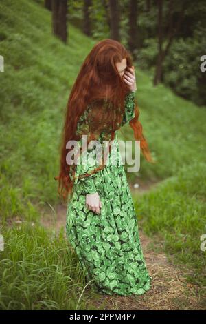 Nahaufnahme einer rothaarigen Frau in langem Kleid, die auf dem Weg steht, Porträtbild Stockfoto