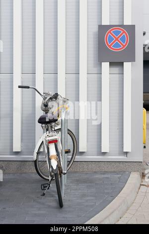 Ich habe ein Fahrrad in einem Supermarkt geparkt, dahinter ein Schild mit dem Hinweis, dass man nicht anhalten darf Stockfoto