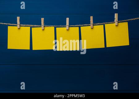 Kleiderschränke mit leeren Notizzetteln auf Garn auf blauem Holzhintergrund. Platz für Text Stockfoto
