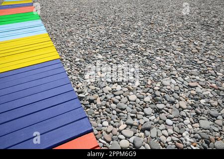 Farbenfroher Holzsteg am Kieselstrand. Platz für Text Stockfoto