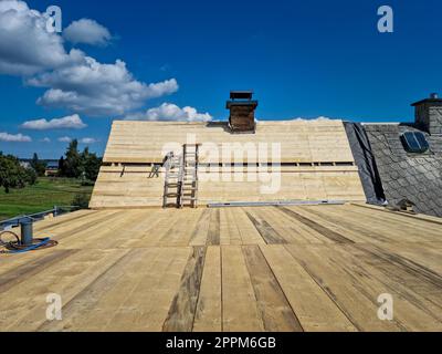 Installation neuer Dachplatten beim Bau des montierten Daches auf dem Haus Stockfoto