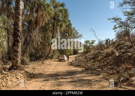 Auto auf einer staubigen Schotterstraße entlang des Flusses Kunene im Norden Namibias Stockfoto