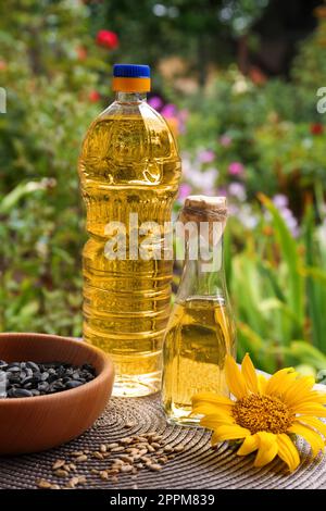 Flaschen mit Sonnenblumenöl und Samen in der Schüssel auf dem Tisch im Freien Stockfoto