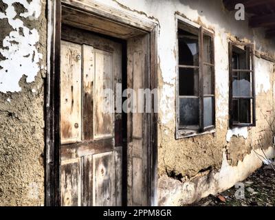 Altes Haus mit Fenstern und einer Tür. Einstürzendes Landhaus. Der Begriff Urbanisierung und Vergessenheit des Mutterlandes. Verlassenes Haus. Zerbrochenes Glas in den Fenstern und herunterfallender Putz. Serbien. Balkan Stockfoto