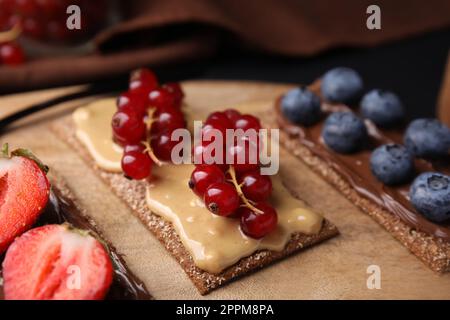 Frisches knuspriges Roggen-Knusperbrot mit verschiedenen Belägen auf Holzbrett, Nahaufnahme Stockfoto