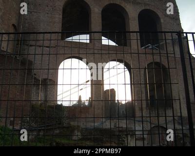 Restaurierung des römischen Kolosseums. Ein Metallzaun um das kolosseum. Die Abendsonne bricht durch hohe Fenster und Öffnungen Stockfoto