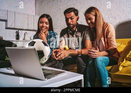 Glückliche Freunde von Fußballfans, die Fußball auf einem Laptop schauen Stockfoto