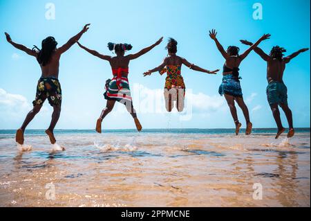 Kenianer springen mit typischen einheimischen Kleidern an den Strand Stockfoto