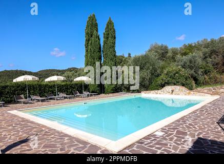 Ein Swimmingpool auf dem Hügel von Montemassi, umgeben von Zypressen und Oleandern. Italien Stockfoto