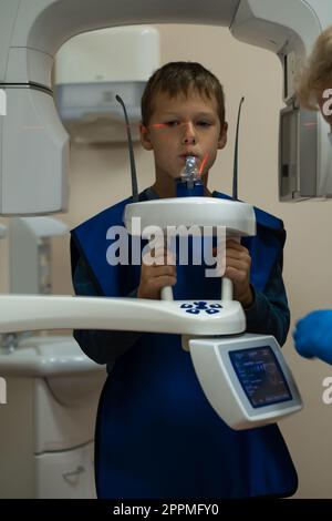 Kiefercomputertomographie, Zahnuntersuchung in der Zahnklinik. Kleiner Junge in der Röntgendiagnostik. Kreisförmige Momentaufnahme der Blende. Stockfoto