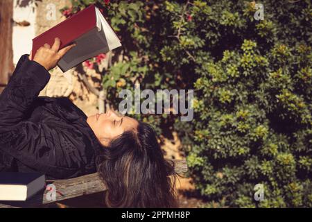 Eine Frau, die ein offenes Buch im Garten hält Stockfoto