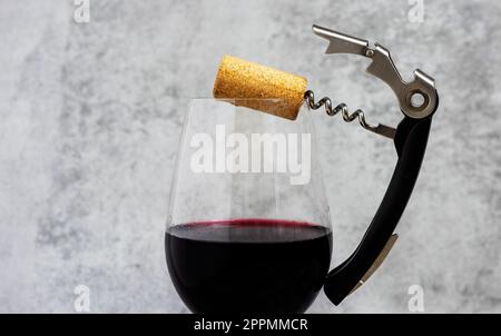Rotwein im Glas mit Brie-Käse am Rand, Kork und Brechschraube Stockfoto