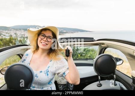 Eine lächelnde Autofahrerin, die neue Autoschlüssel und ein neues Auto zeigt. Weibliche Fahrerin mietete Cabrio im Sommerurlaub Stockfoto