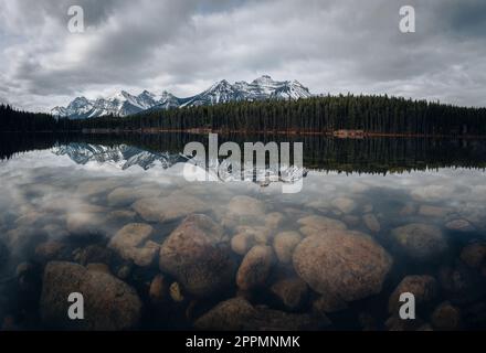 Herbert Lake in Alberta, Kanada an einem bewölkten Tag mit atemberaubenden Bergen und Wasserreflexionen Stockfoto