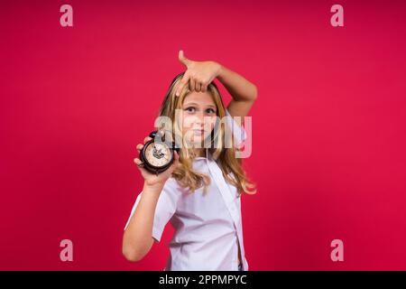 Teenager Mädchen 12, 13, 14 Jahre, schauen auf den Wecker. Guten Morgen, wir überprüfen die Zeit. Positive Emotionen. Stockfoto