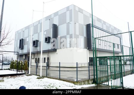 Sremska Mitrovica, Serbien, 27. Januar 2023 City Swimming Pool Building. Pinky Swimming Pool, neben dem Pinky Sports Centre. Modernes Sportgebäude mit einer grau-weiß belüfteten Fassade. Schnee im Winter. Stockfoto