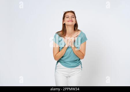 Glückliche junge Frau mit einem Lächeln und gefalteten Händen, die auf weißem Hintergrund posieren. Stockfoto