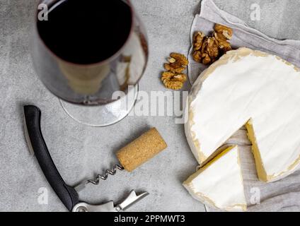 Rotwein im Glas mit Brie-Käse am Rand, Kork und Brechschraube Stockfoto