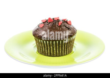 Isolierte Schoko-Muffin mit roten Zuckerherzen auf einem Teller grün Stockfoto