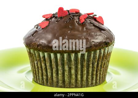 Isolierte Schoko-Muffin mit roten Zuckerherzen auf einem Teller grün Stockfoto