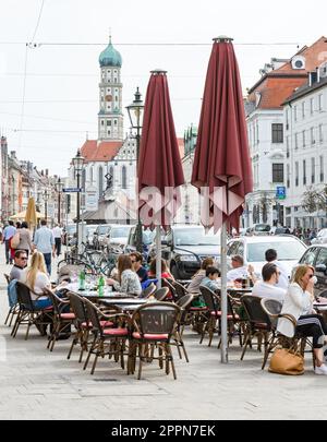 AUGSBURG - 1. APRIL: Menschen in einem Straßencafé in Augsburg am 1. April 2017. Augsburg ist eine der ältesten Städte Deutschlands. Foto Stockfoto