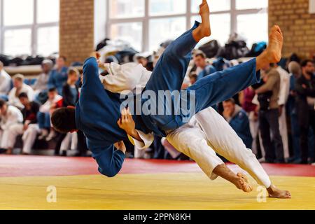 Judoka in weißem Kimono landet seinen Gegner in blauem Kimono zurück, Judo-Kampfwettbewerb Stockfoto