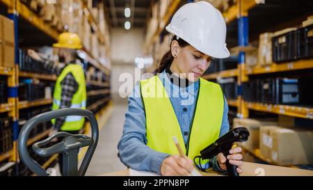 Lagerarbeiter prüfen mit digitalem System Sachen im Lager. Stockfoto