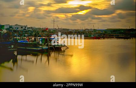 Fischerdorf in Kamal, Jakarta, Indonesien, mit festgefahrenen Booten. Bewegungsunschärfe bei sich bewegenden Booten. Langzeitbelichtung. Stockfoto