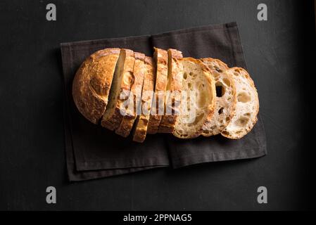 Frisches hausgemachtes Sauerteigbrot. Brotscheiben auf schwarzem Hintergrund. Stockfoto