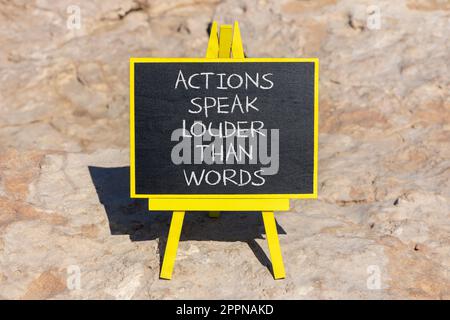 Das Symbol „Aktionen sprechen lautere Wörter“. Begriffliche Wörter Taten sprechen lauter als Worte auf schwarzer Tafel auf einem wunderschönen Steinhintergrund. Geschäftserfolge Stockfoto