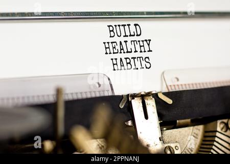 Motivation gesunde Gewohnheiten aufbauen Symbol. Konzeptwörter entwickeln gesunde Gewohnheiten auf weißem Papier, das auf einer alten Retro-Schreibmaschine auf einem wunderschönen weißen Hintergrund getippt wird. Stockfoto