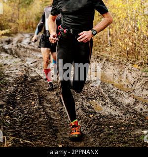 Männlicher Läufer, der im Herbst auf einem unpassierbaren Dirt-Road-Marathon läuft, Cross-Country-Rennen Stockfoto