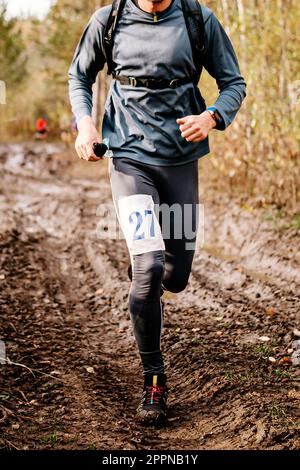 Sportlerläufer, der auf dem Herbstmarathon auf der unpassierbaren Straße läuft, Sportnummer auf Beinjogger Stockfoto