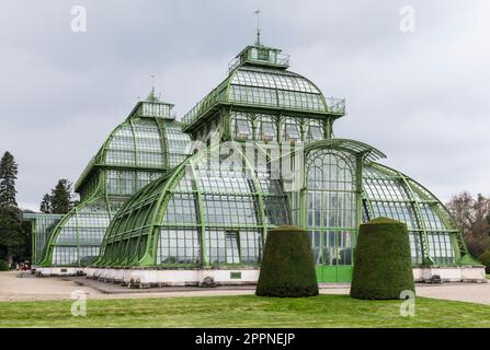 Die Kuppeln des Palmenhauses aus Schmiedeeisen, Gusseisen und Glas im Schlosspark Schönbrunn unter grauem Himmel, Wien, Österreich Stockfoto