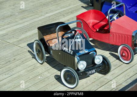 Treten Sie Autos in altem Stil für Kinder zum Spielen im Freien auf dem Spielplatz aus Holz in die Pedale. Stockfoto