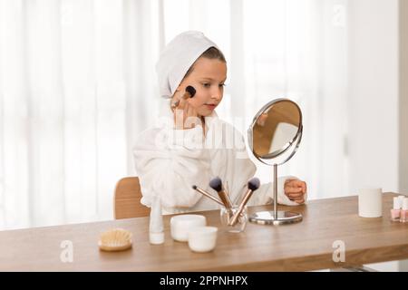 Süßes Kleines Mädchen Im Weißen Bademantel Make-Up Zu Hause Auftragen Stockfoto