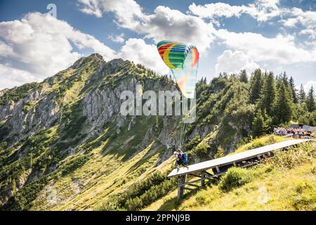 SCHWANGAU - 23. AUGUST: Unbekannter Gleitschirmflieger auf dem Tegelberg in Schwangau am 23. August 2015. Tegelberg ist einer der beliebtesten Stockfoto